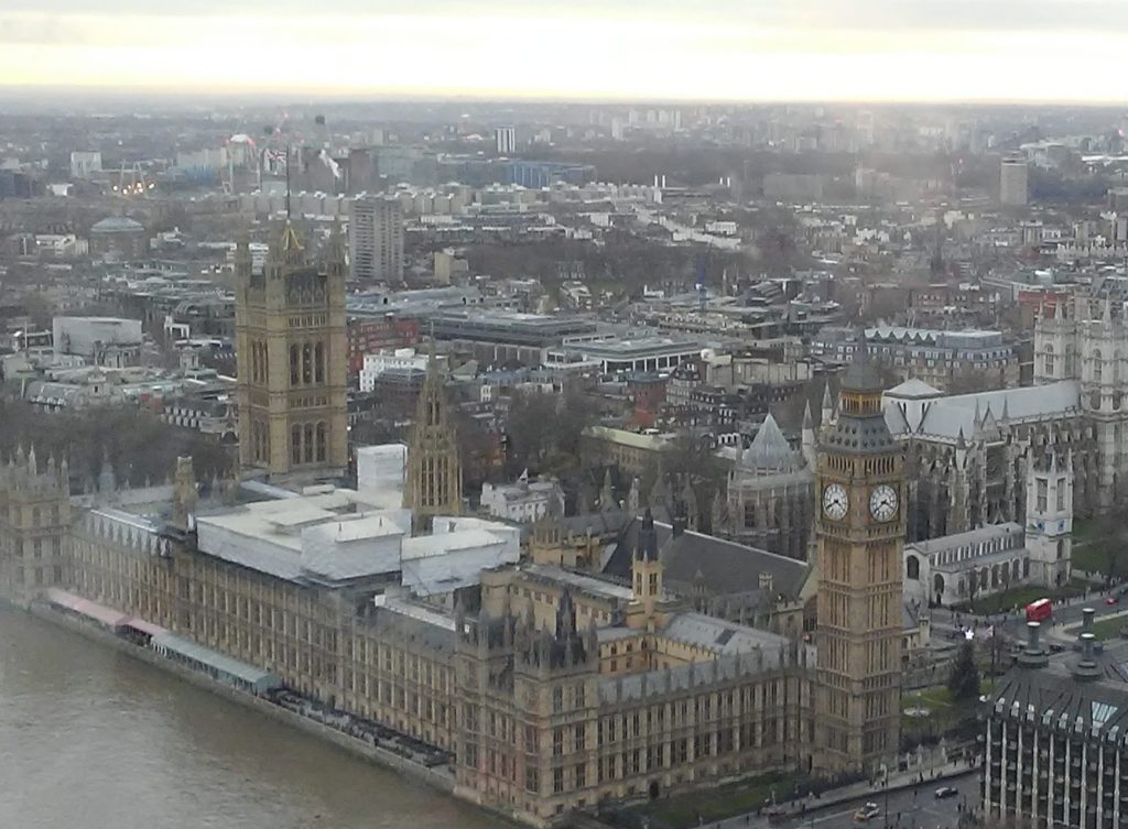 Aerial view of London showcasing the iconic Big Ben and Houses of Parliament along the River Thames, with cityscape in the background.
