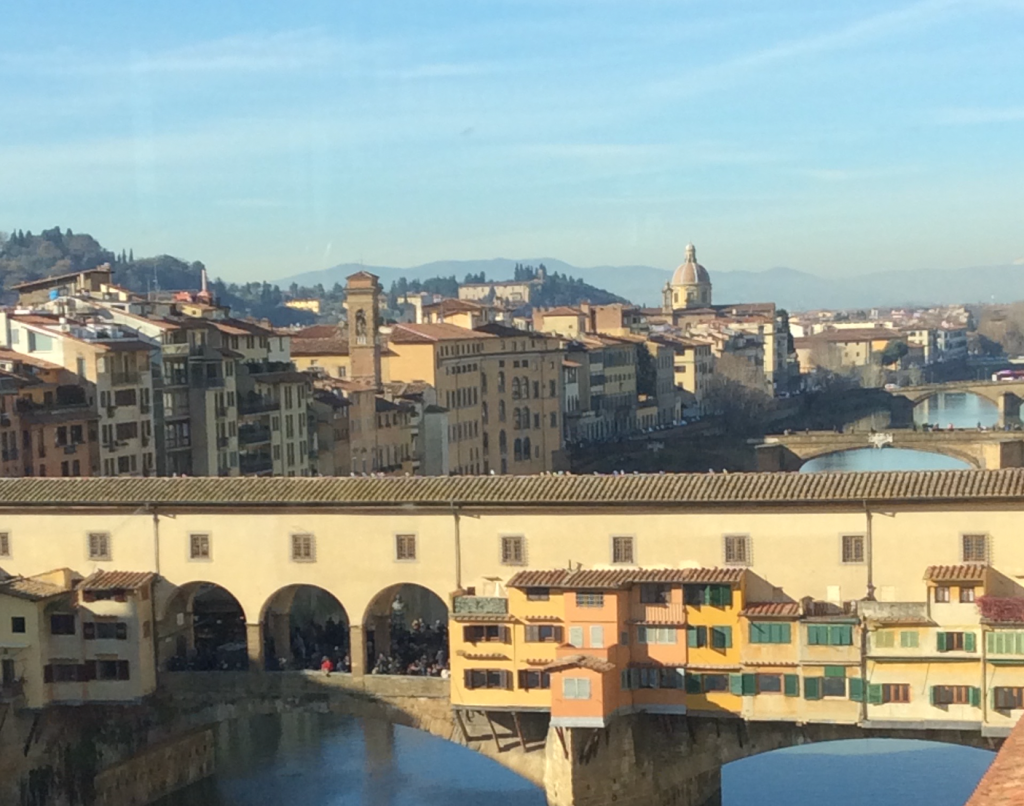 Ponte Vecchio bridge in Florence, Italy, showcasing colorful buildings and reflections in the water, a historic landmark.